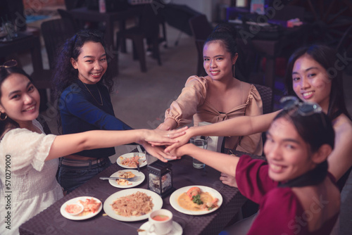 Young female millennial entrepreneurs proudly show positive relationship with a huddle while they happily smile for the camera. Ending a business meeting with a huddle.