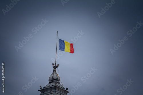 Flag of Romania, also called Drapelul Romaniei waiving on a flagpole of Timisoara, in front of a grey cloudy sky. It is the national symbol of Romania.. photo