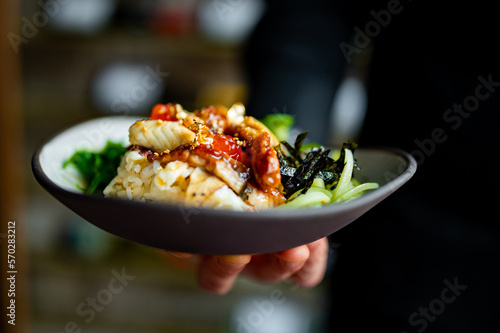 Fototapete chef holding delicious donburi bowl with fish, rice and vegetables