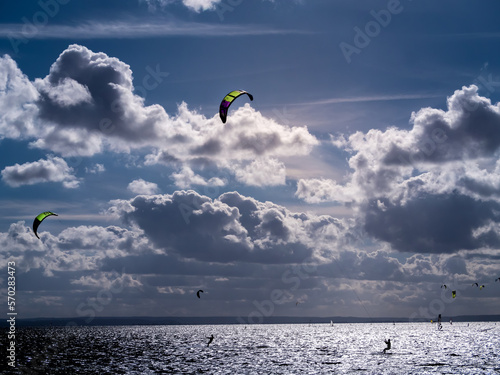 Backlit silhouettes of kitesurfers