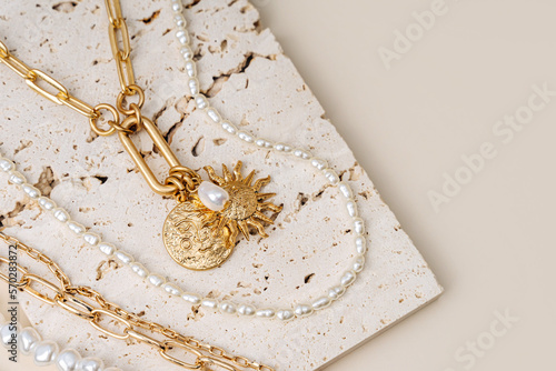 Trendy jewelry with chains, pearl necklace and pendant shapes moon and sun. Stylish golden bijouterie on the stone. Fashion accessories.