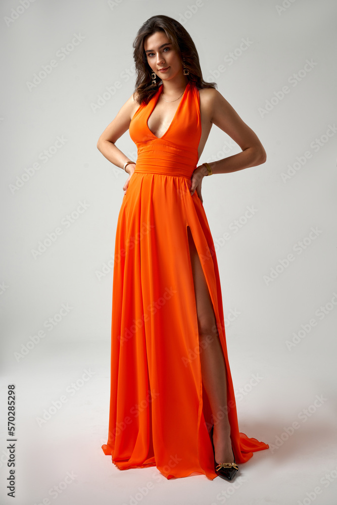 Sexy Fashion Model in Orange Dress showing Leg over Gray Background Sexy Fashion Model in Orange Dress showing Leg over Gray Background
