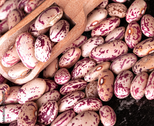 Raw light beans in a wooden spoon on a pile of beans. Top view