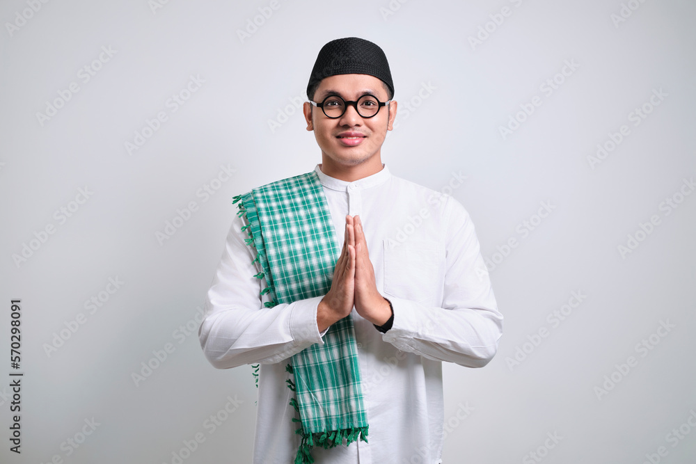 Asian Muslim man wearing white clothes smiling to give greeting during Ramadan and Eid Al Fitr celebration Asian Muslim man wearing white clothes smiling to give greeting during Ramadan and Eid Al Fitr celebration