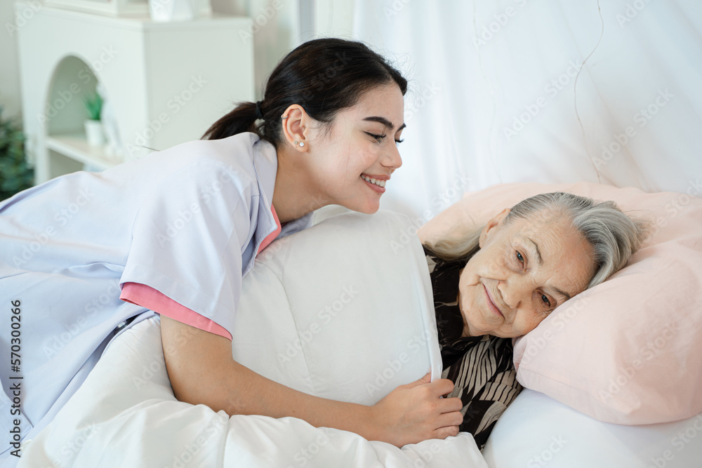 Nurse support supporting senior woman on bed in bedroom at nursing home,Senior services and geriatric care concept. Nurse support supporting senior woman on bed in bedroom at nursing home,Senior services and geriatric care concept.