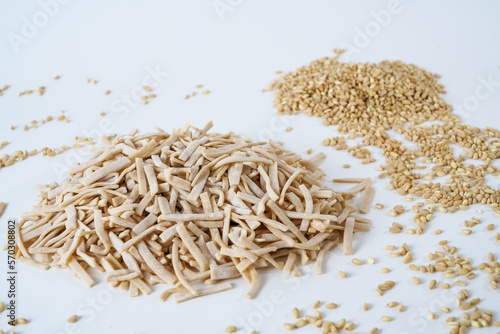 Uncooked homemade egg noodles and coarse bulgur wheat grains isolated on white background.