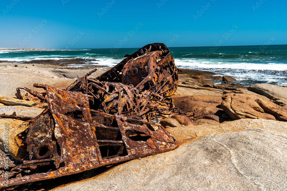 A rusty ship wreck lies on the rocks at the Atlantic Ocean Coast in South Africa.
