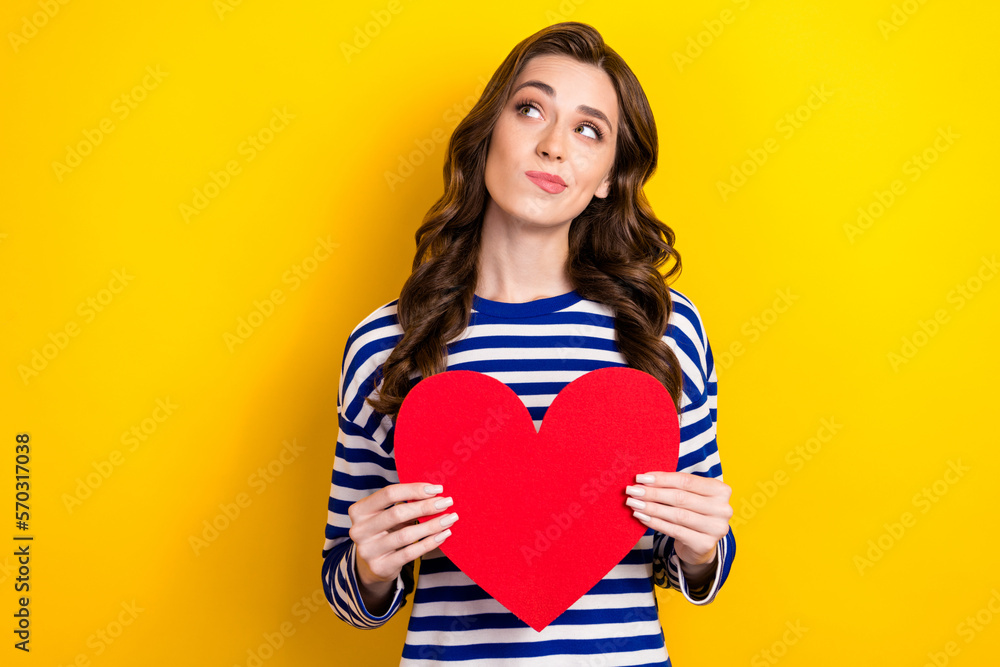 Photo of young minded hmm thinking woman wear striped trendy jumper hold paper red like symbol dreamy look mockup isolated on yellow color background Photo of young minded hmm thinking woman wear striped trendy jumper hold paper red like symbol dreamy look mockup isolated on yellow color background