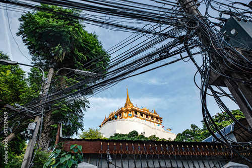 Phra That Phukhao Thong viewed through tangled wires perched on a hill in Wat Saket, Bangkok, Thailand. photo