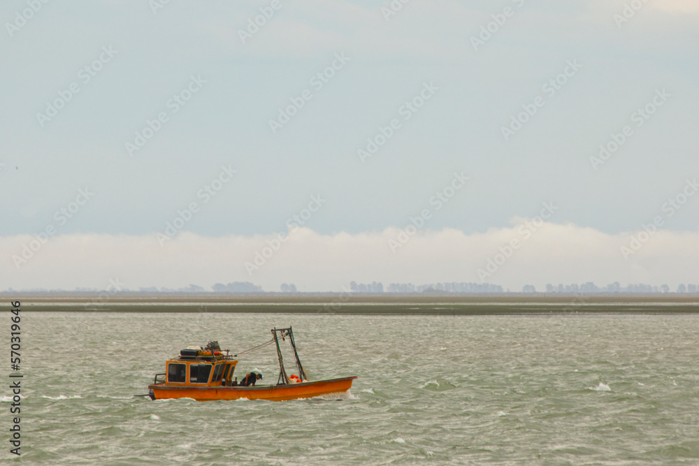 Small fishing boat approaching the coast in a stormy sea