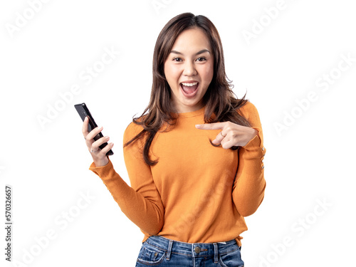 Photo features a happy Indonesian woman wearing an orange sweater and jeans while holding a smartphone, isolated on a white background.