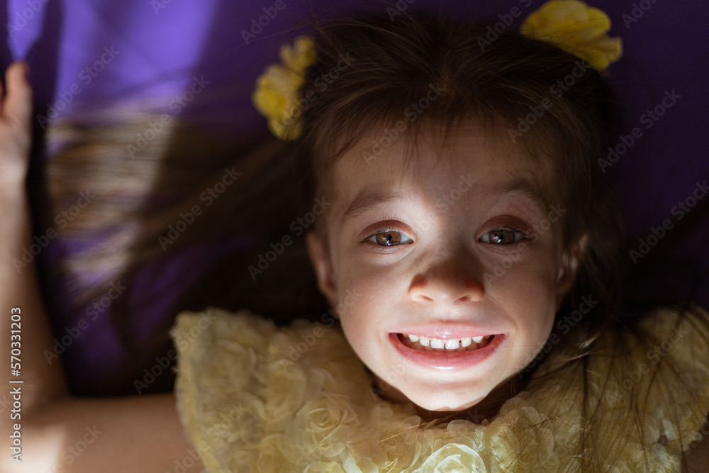 Cute girl smiling and lying on the floor
with sun glare Cute girl smiling and lying on the floor
with sun glare