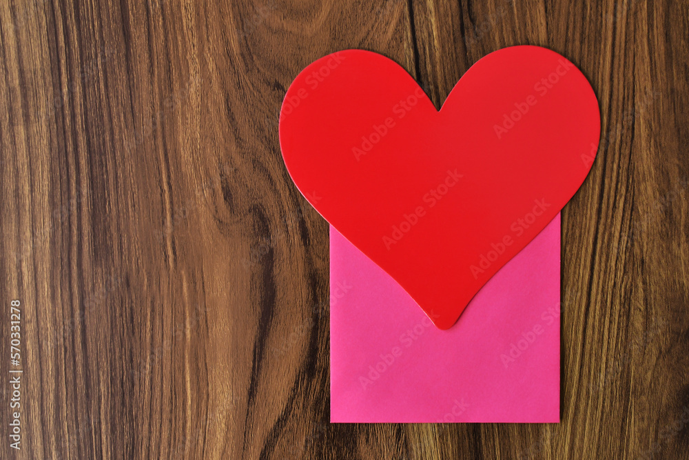 Fototapeta premium Corazón rojo sobre una mesa de madera, espacio para texto al lado izquierdo.