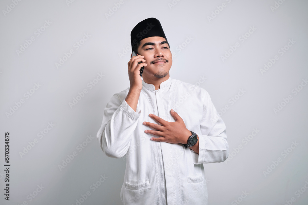 Happy asian muslim man in white clothes doing phone call with his family during ramadhan or Eid Al Fitr Happy asian muslim man in white clothes doing phone call with his family during ramadhan or Eid Al Fitr