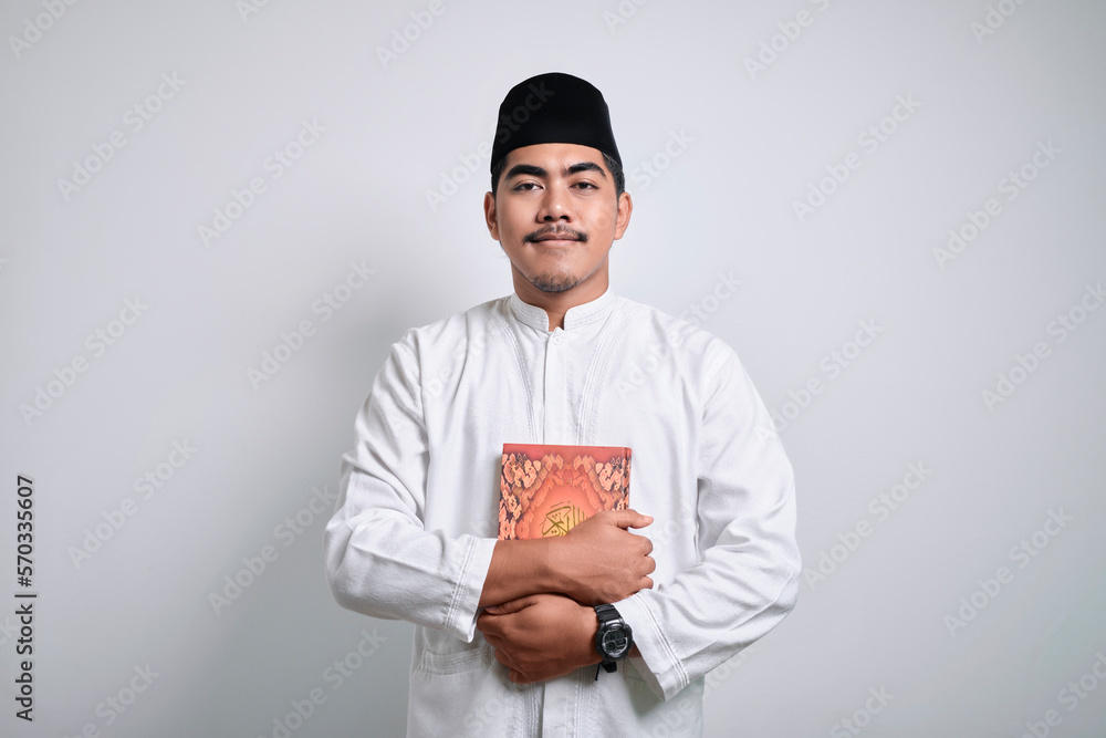 Portrait of a smiling asian muslim man holding the quran Portrait of a smiling asian muslim man holding the quran