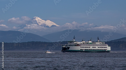 A small powerboat and a Washington State Ferry transit the San Juan Islands near Anacortes, Washington with a stately Mount Baker towering in the background.