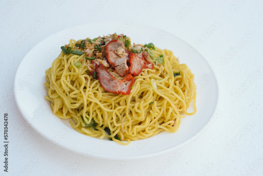 Selective focus on stir fried yellow noodle with pork and vegetables on dish, white  background. Concept, traditional food, delicious, easy to cook or can order from Thai restarant of street food