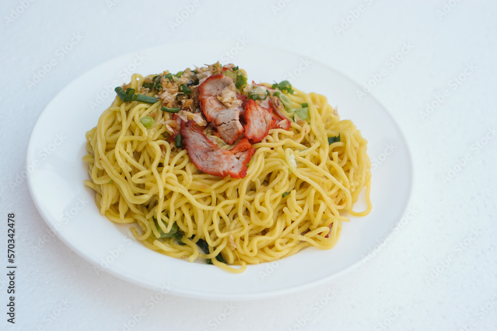 Selective focus on stir fried yellow noodle with pork and vegetables on dish, white background. Concept, traditional food, delicious, easy to cook or can order from Thai restarant of street food Selective focus on stir fried yellow noodle with pork and vegetables on dish, white background. Concept, traditional food, delicious, easy to cook or can order from Thai restarant of street food