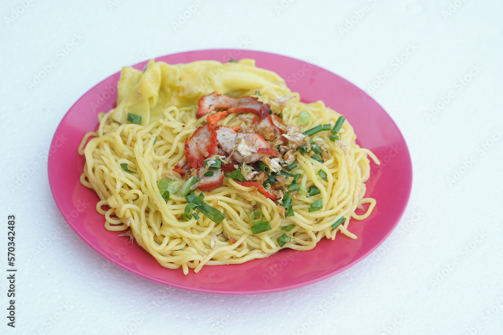 Selective focus on stir fried yellow noodle with pork and vegetables on dish, white  background. Concept, traditional food, delicious, easy to cook or can order from Thai restarant of street food     