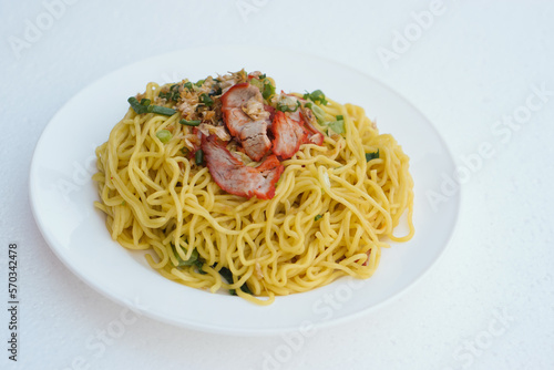 Selective focus on stir fried yellow noodle with pork and vegetables on dish  white  background. Concept  traditional food  delicious  easy to cook or can order from Thai restarant of street food