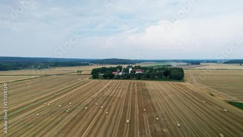 Aerial Arc Shot of a church surrounded with Woodland and gold yellow meadows. In the background farms and low mountains with forests. Gammalstorp Kyrka in Sölvesborg Sweden photo