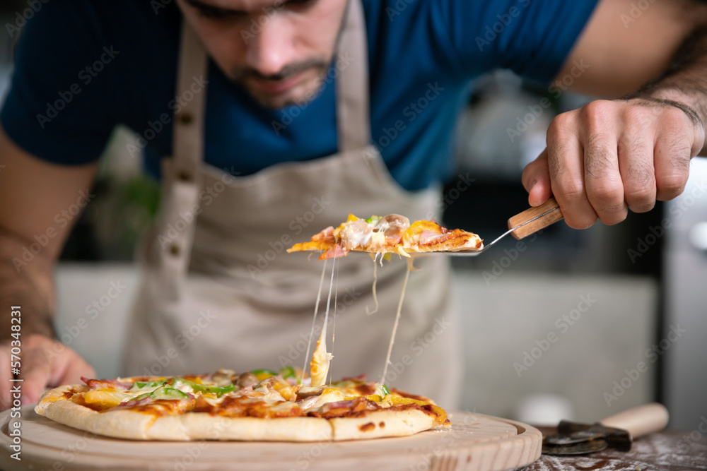 handsome chef cut delicious homemade italian mozzarella pizza after prepare and bake from stove or oven for lunch meal or dinner in local italian pizza restaurant handsome chef cut delicious homemade italian mozzarella pizza after prepare and bake from stove or oven for lunch meal or dinner in local italian pizza restaurant