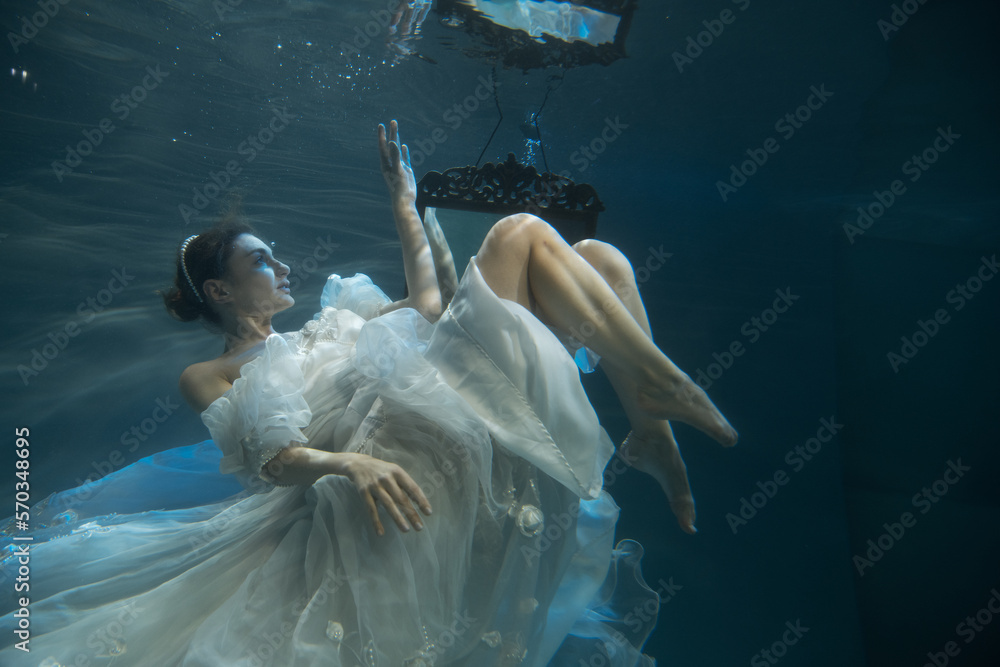 Naklejka premium Young woman in wedding dress under water