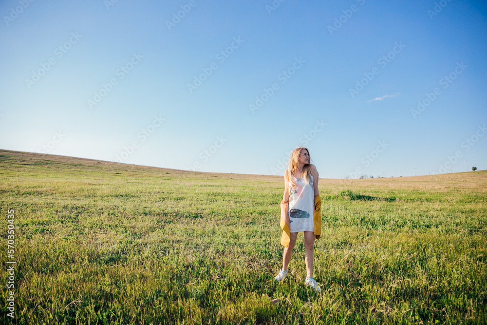 blonde woman in yellow clothes in nature green meadow