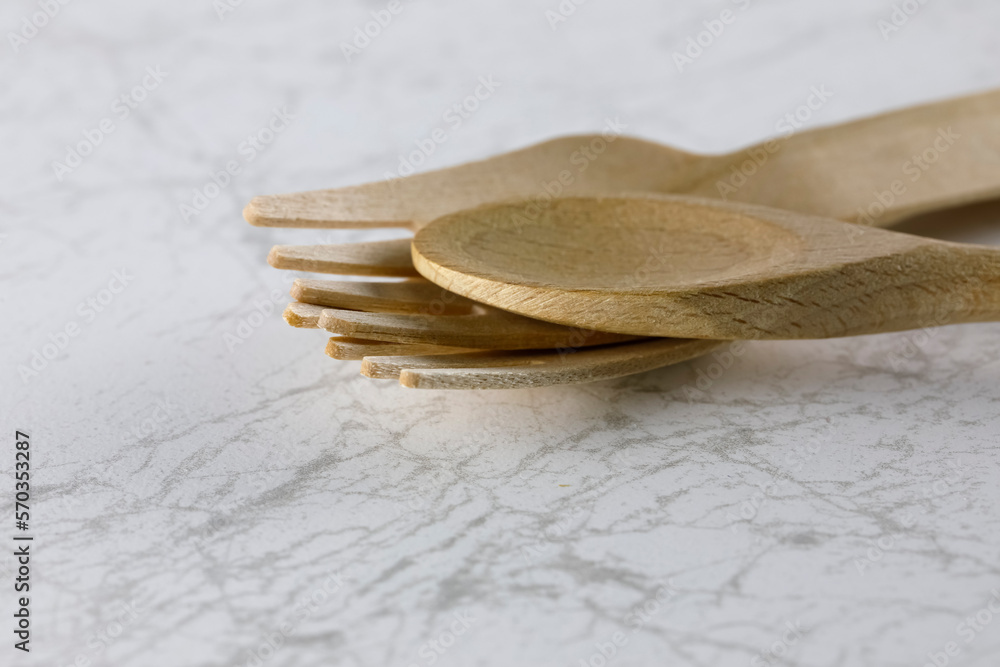 Wooden cutlery lies on a marble table Wooden cutlery lies on a marble table