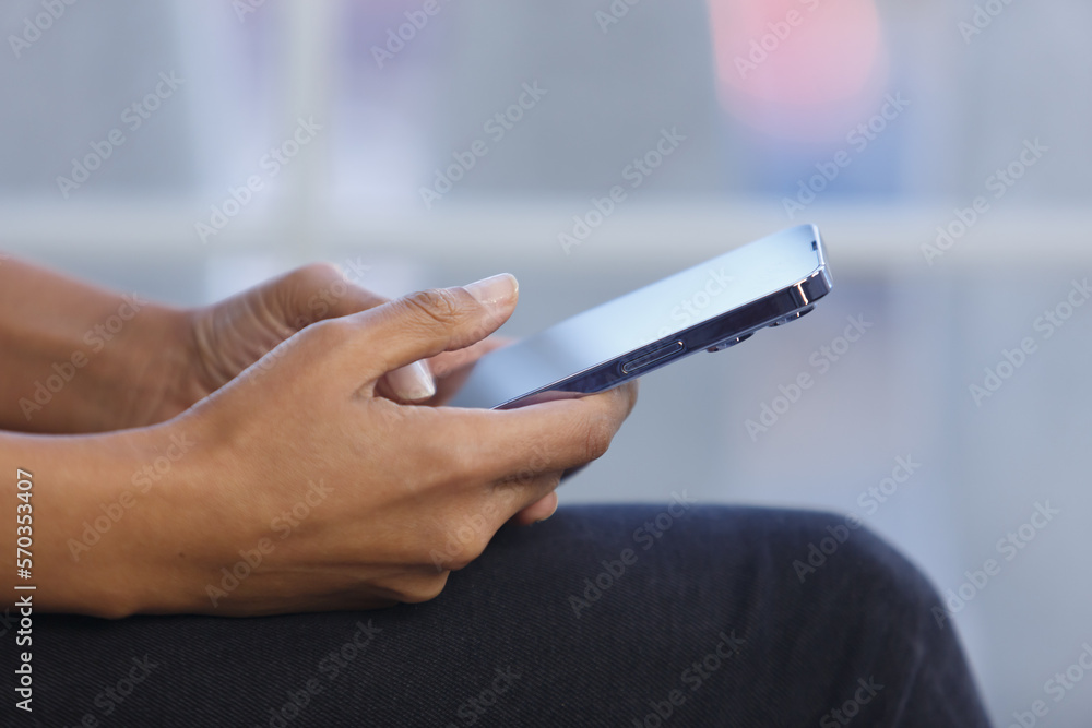 Hands of black female person typing a message on smart phone. Young adult POC woman using modern mobile phone with big touch screen Hands of black female person typing a message on smart phone. Young adult POC woman using modern mobile phone with big touch screen
