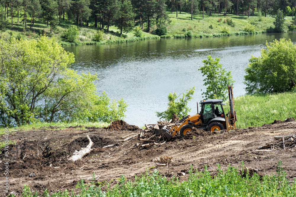 tractor works in the park for landscaping next to the river tractor works in the park for landscaping next to the river