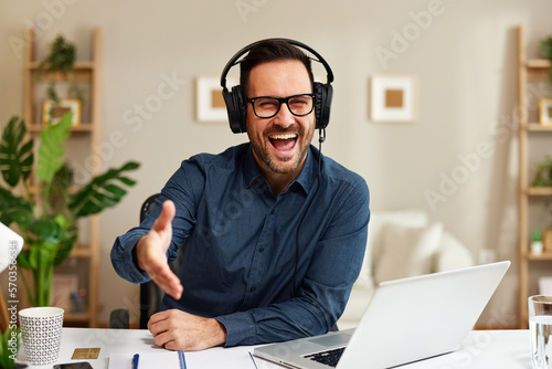 Fotografia Handsome customer support man with a smile on his face is sitting at a desk and