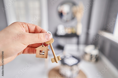 Concept of renting an apartment. House key in man hand. Young man. Modern light lobby interior. Real estate, hypothec, moving home or renting property.