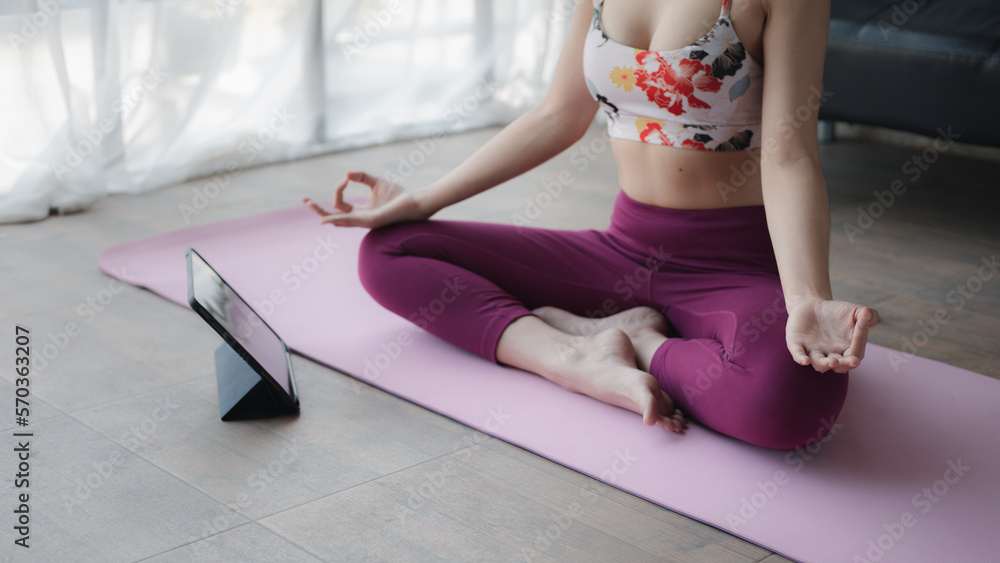 Obraz premium Young asian woman doing yoga in living room, yoga poses for exercise and meditation, doing yoga postures for body and mind balance, exercise for a healthy body. Yoga concept.