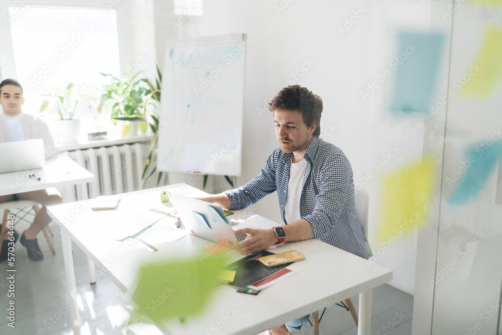 Focused man working on laptop in creative workspace Focused man working on laptop in creative workspace
