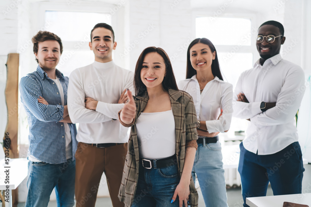 Diverse colleagues standing in row while female coworker with thumb up Diverse colleagues standing in row while female coworker with thumb up