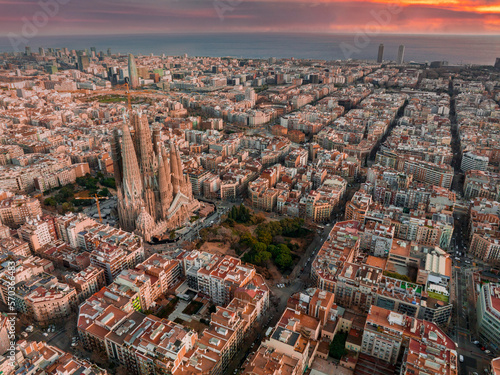 Aerial view of Barcelona City Skyline and Sagrada Familia Cathedral at sunset. Eixample residential famous urban grid. Cityscape with typical urban octagon blocks