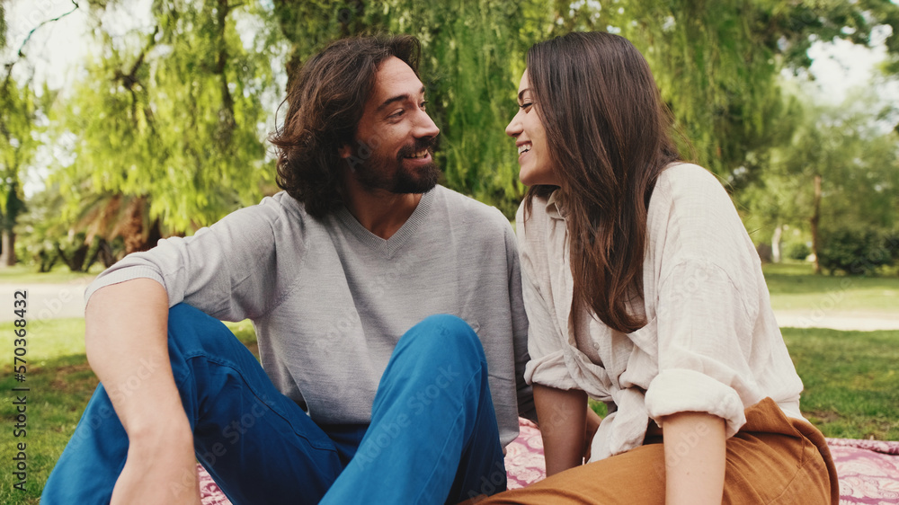 Happy smiling couple talking while sitting on blanket in park. Close-up Happy smiling couple talking while sitting on blanket in park. Close-up