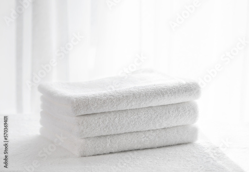 Three white terry bath towels on a light background in the bathroom