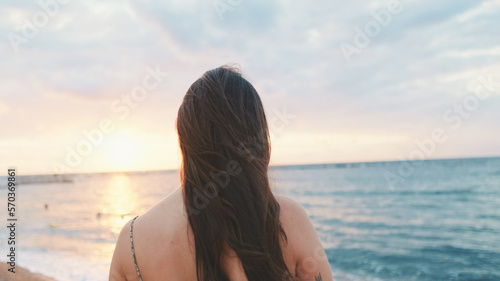 Close-up of young attractive woman on the beach, back view