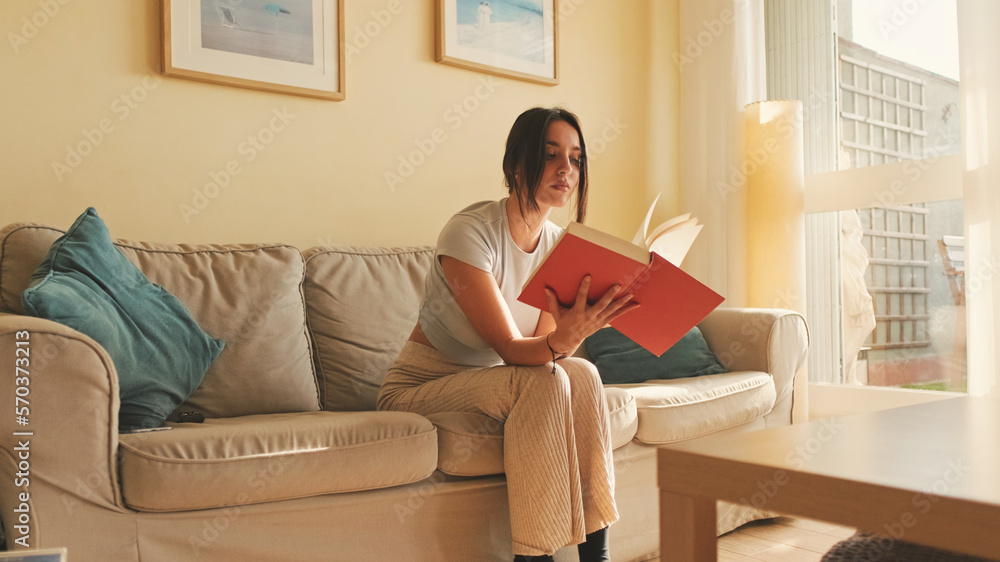 Young woman reading book sitting on the sofa at home Young woman reading book sitting on the sofa at home