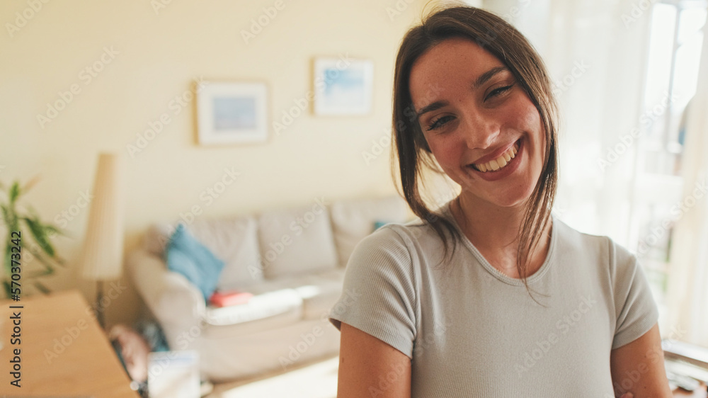 Close up, young beautiful woman crossing her arms and smiling at camera while standing at home Close up, young beautiful woman crossing her arms and smiling at camera while standing at home