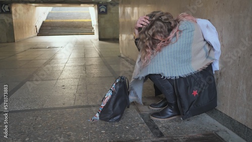 A lonely, sad girl sitting in an underpass.