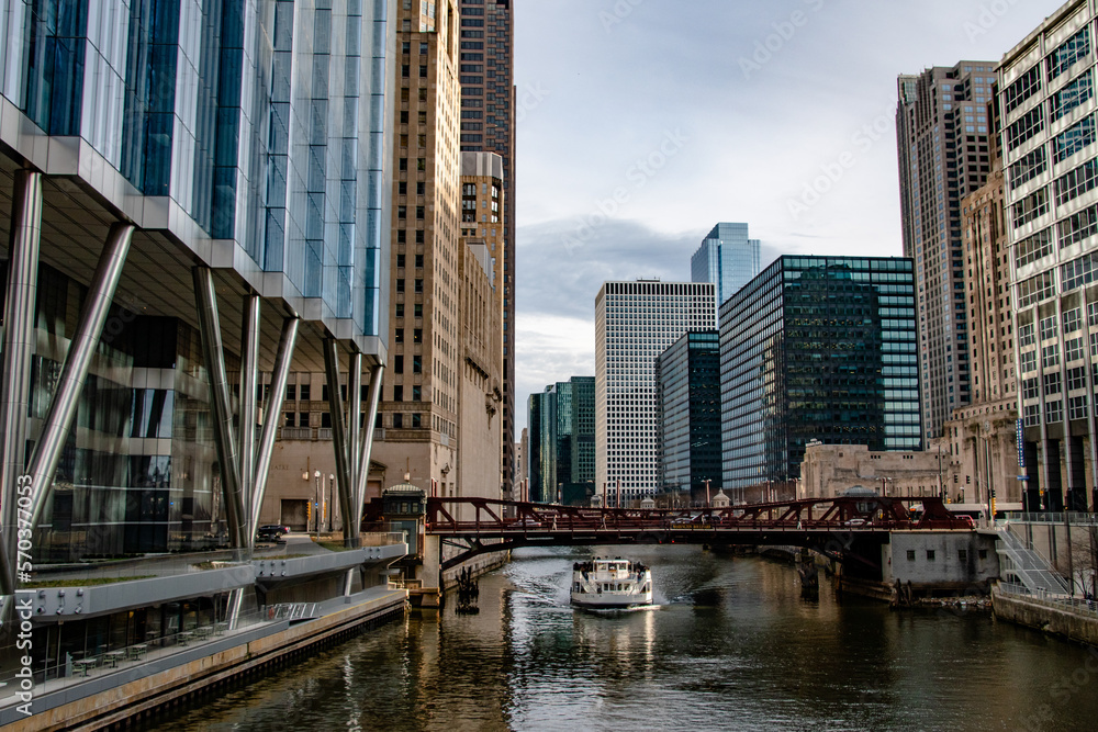 Obraz premium Tour Boat Cruising the Chicago River Giving Tours to the Architecture in in Downtown Chicago, IL