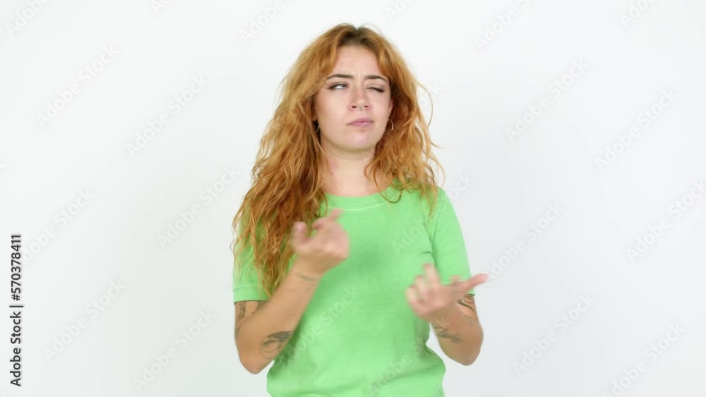 Young redhead woman pointing to the laterals having doubts over isolated background Young redhead woman pointing to the laterals having doubts over isolated background