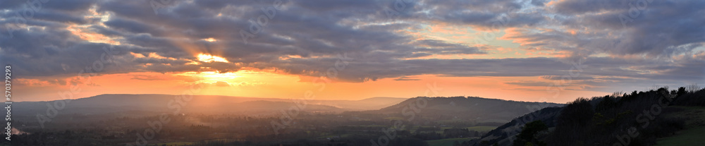 Sunset panoramic view from Colley Hill between Reigate and Dorking in Surrey, UK. Surrey Hills area of Outstanding Natural Beauty on the North Downs. Looking towards Leith Hill on the Greensand Ridge.