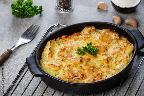 Potato casserole with cheese and parsley on stone background. French cuisine