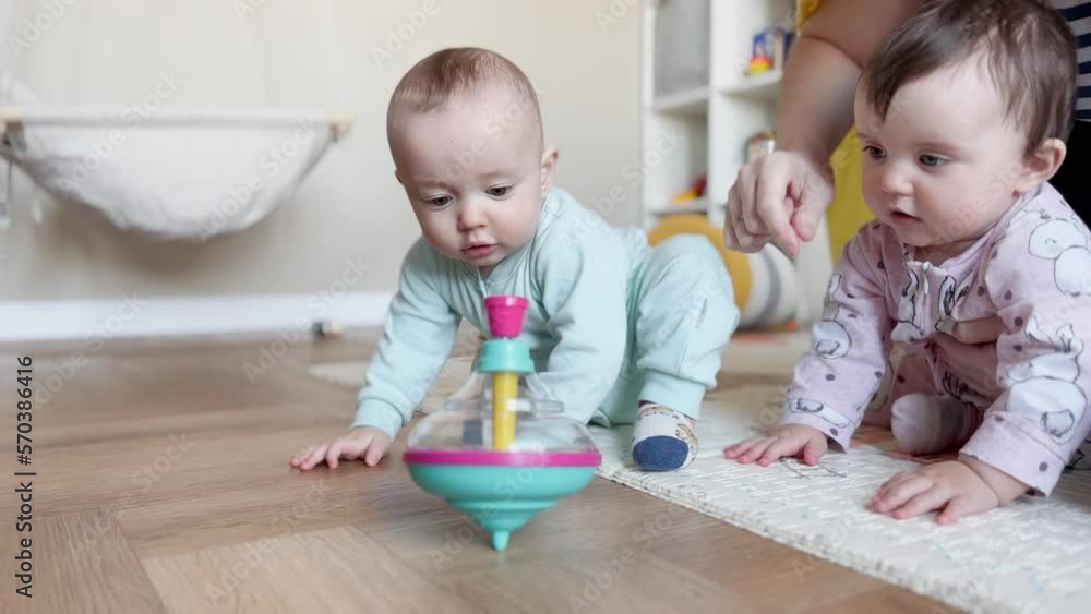 baby group playing spinning top toy. kindergarten a happy childhood concept. baby twins with mom play toy whirligig indoors. baby group in kindergarten with a teacher play top in lifestyle playroom baby group playing spinning top toy. kindergarten a happy childhood concept. baby twins with mom play toy whirligig indoors. baby group in kindergarten with a teacher play top in lifestyle playroom