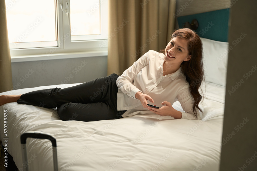 Woman is located on bed with phone in her hands Woman is located on bed with phone in her hands