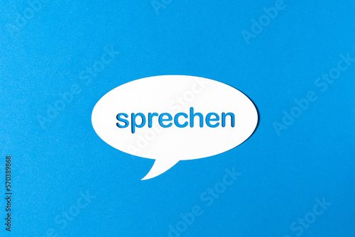 Deutsches Wort sprechen in einer Sprechblase aus Papier ausgestanzt vor blauem Hintergrund. Fotorealistischer Vektor.
